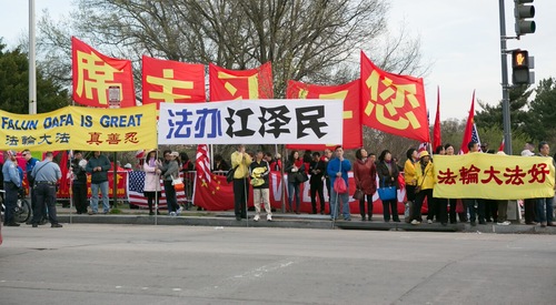 Falun Gong practitioners hold banners in front of Xi's hotel. The white banners with blue and black texts read: “Bring Jiang Zemin to Justice.”