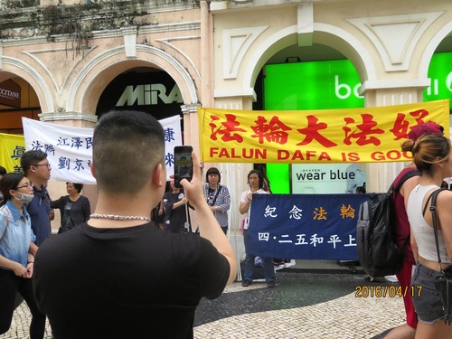 A Chinese tourist takes photos of the Falun Gong event.