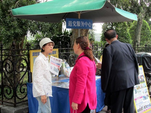 A Falun Gong practitioner (in white) talks to a Chinese tourist about quitting the Chinese Communist Party.