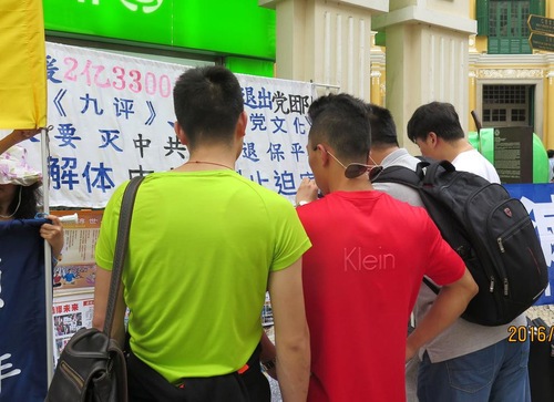 Chinese tourists read about Falun Gong.