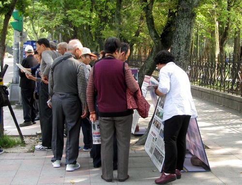 Chinese tourists study the Falun Gong materials.