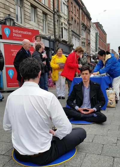 Thomas (in black jacket), who came from France six months ago, learns the exercises from a practitioner. After doing the sitting meditation for 30 minutes, he said that he felt energy circulating in his body.