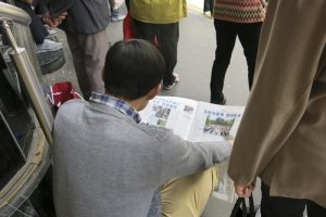 Chinese tourists read Falun Gong informational materials in front of Galeries Lafayette.