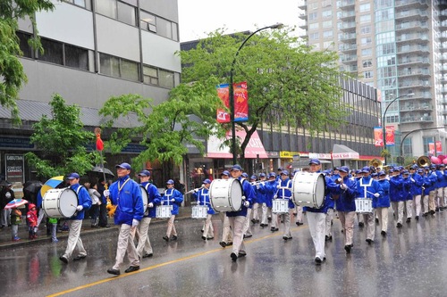 The Divine Land Marching Band leads the Falun Dafa practitioners in a pouring rain during the 45th annual Hyack International Parade in New Westminster.