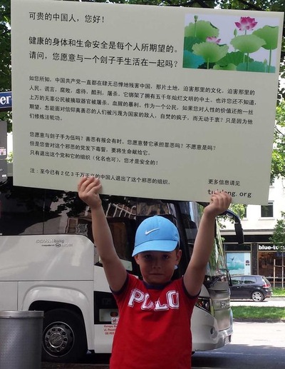 A young practitioner upholds a poster with Chinese information to raise awareness on the nature of the Communist Party, and advise withdrawal from it.