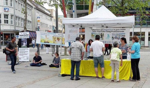 Passersby in Heidenheim an der Brenz pause at the practitioners' booth to learn about Falun Gong.
