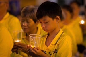 A boy holds a candle in memory of Falun Gong practitioners tortured to death for refusing to renounce their faith in mainland China.