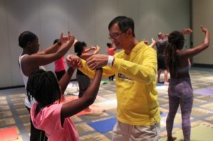 A practitioner teaches a young person the hand gestures of the Falun Gong exercises.