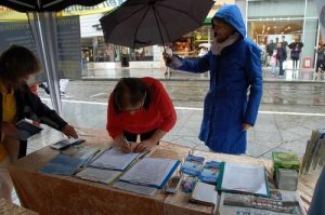 A passerby pauses to sign the petition, despite the rain.