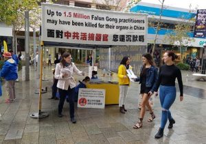 Falun Gong practitioners distribute flyers to passersby.