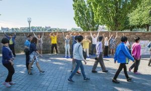 A Chinese tour group walks by Falun Gong practitioners demonstrating the exercises along the route to the Stockholm City Hall.