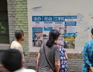 Passersby read a poster in Nanchang City, Jiangxi Province, that expose how former Chinese leader Jiang Zemin has brutally persecuted Falun Gong practitioners for their belief.