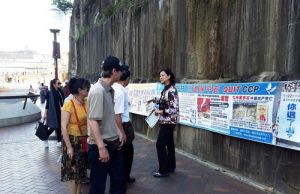 A practitioner (right) talks to Chinese tourists about the persecution of Falun Gong in China.