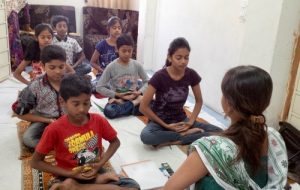 A practitioner leads the children in meditation.