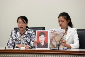 Chi Lihua (left) and her daughter Xu Xinyang (right) at the forum. Xu is holding two pictures of her father Xu Dawei. The photo on the left was taken before Xu Dawei was arrested, and the one on the right shows him after he was released.