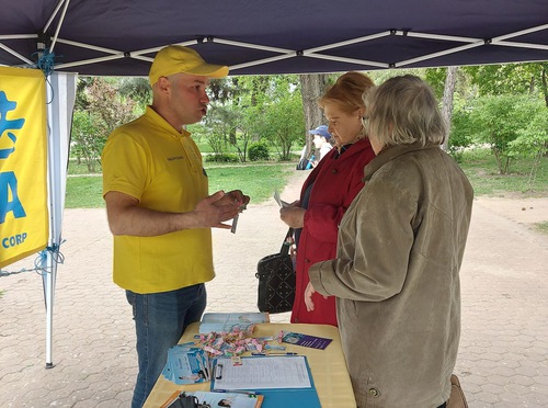 The practitioner tells bystanders the facts about the persecution committed against Falun Gong in China.

