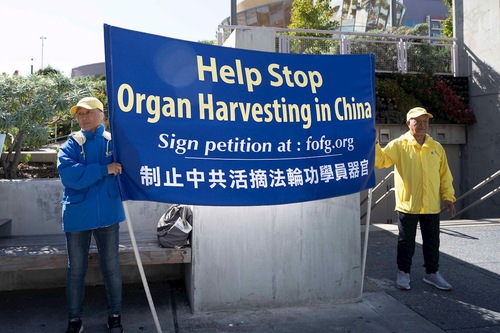Falun Dafa practitioners held up banners outside the World Transplant Congress venue on August 3, 2025.

